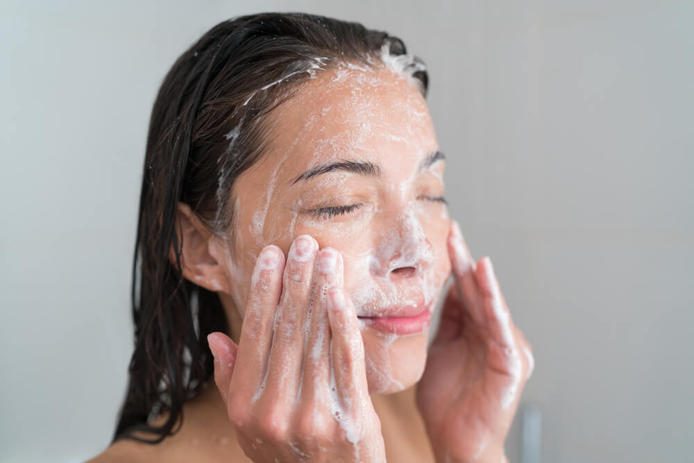 A Woman Cleaning Her Face With Cleanser